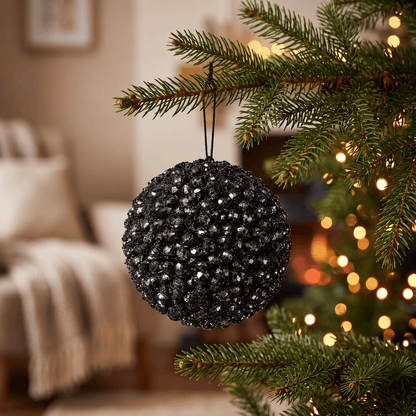 Foam Cluster Bauble - Black Glitter - 15cm, hanging on a Christmas tree with warm white fairy lights, featuring sparkling black clusters and reflective glitter detailing.