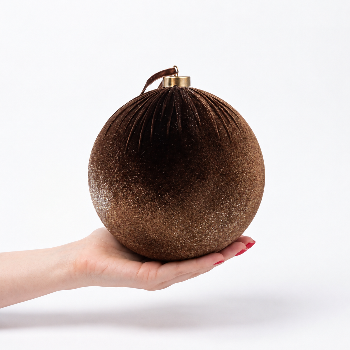Brown velvet Christmas bauble decoration 20cm with soft textured finish and gold cap, displayed in the palm of a hand against a plain light background.