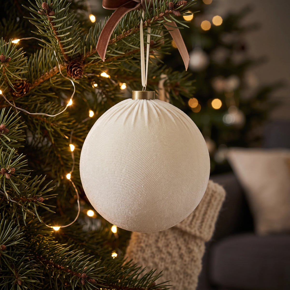 Velvet Bauble – Cream – 15cm, hanging on a Christmas tree decorated with warm white fairy lights, brown velvet ribbons and elegant neutral festive decorations.